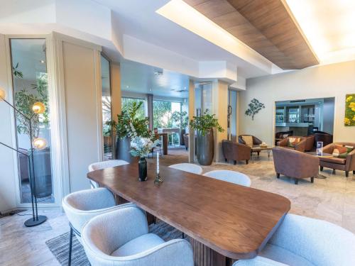 a dining room with a wooden table and chairs at Mercure Besancon Parc Micaud - Hotel & Bar in Besançon