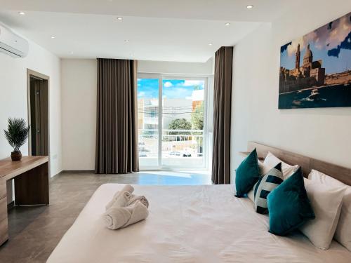 a bedroom with a bed with towels on it at Modern Escape Villa in St Julian w Pool by ArcoCollection in St. Julianʼs
