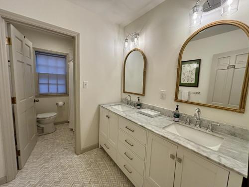 a bathroom with two sinks and a toilet and a mirror at Historic Wayne Street - close to the Stadium in South Bend
