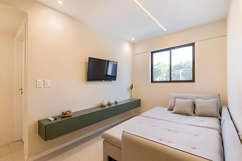 a bedroom with a bed and a tv on the wall at Edifício Mosaico do Mar - Seu Refugio na Praia da Jatiúca in Maceió