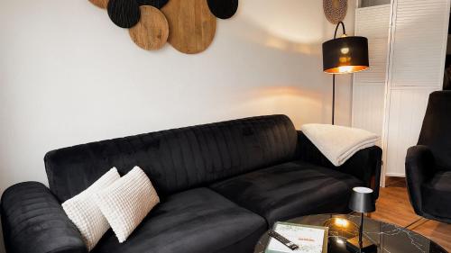 a black couch in a living room with a table at Gemütliches Ferienapartment Für jedes Budget in Horhausen