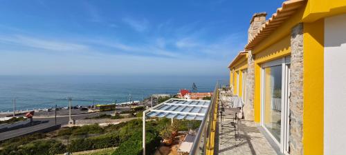 a yellow building with a view of the ocean at Mega Ocean Magoito - Guest House - Sintra in Sintra