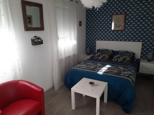 a bedroom with a bed and a red chair at la conviviale in Bénouville