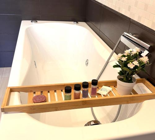 a bath tub with a shelf with cosmetics and flowers at Relax a 20 minuti da Roma - Ampio, Silenzioso e con 2 Bagni in Monterotondo