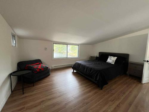 a bedroom with a bed and a chair and a window at Chalet lac Chantelle in Chertsey