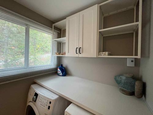a kitchen with white cabinets and a washing machine at Chalet lac Chantelle in Chertsey