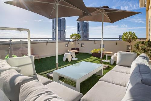 a patio with a couch and tables and an umbrella at Eurostars Atlántida in Santa Cruz de Tenerife