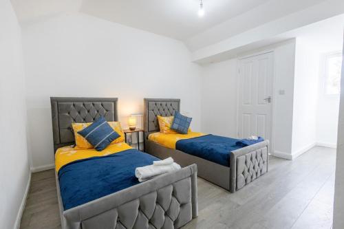 a bedroom with two beds with blue and yellow at The Robinwood Green Haven Retreat Luxurious 3 Bedroom Stay Sleeps 7 in Nottingham