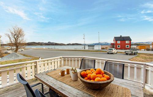 Lovely Home In Abelvær With Wifi في Abelvær: وعاء من البرتقال على طاولة خشبية في شرفة