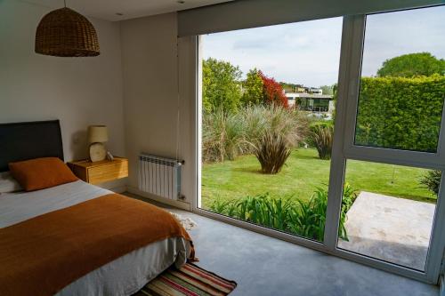a bedroom with a large window with a view of a yard at Casa Angelica - Casa en Barrio Cerrado Arenas del Sur para 6 PAX con Pileta y Parilla in Mar del Plata