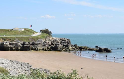 a beach with people standing on the sand and the ocean at Gorgeous Home In Dompierre-Sur-Charente in Dompierre-sur-Charente