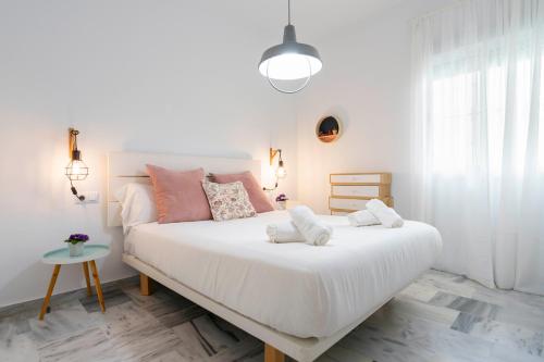 Un dormitorio con una gran cama blanca con almohadas rosas. en Alohamundi Rocío, en Sevilla