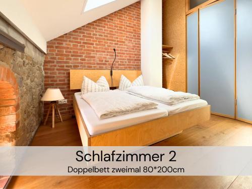a bed in a room with a brick wall at HexenburgbeiDresden Maisonette über 2 Etagen mit 4 Schlafzimmern, Kamin, Terrasse und Faßsauna, Nähe Sächsische Schweiz Dresden in Großharthau