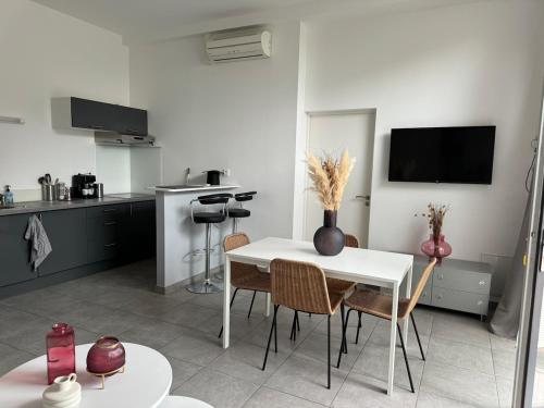 een witte keuken met een witte tafel en stoelen bij Joli studio de 30 m2 in Laval