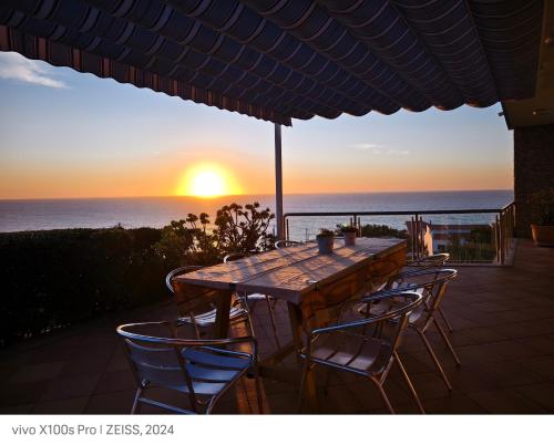 a table and chairs on a patio with a view of the ocean at Mega Ocean Magoito - Sintra in Sintra