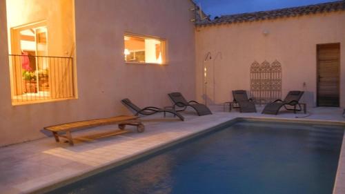a pool with chairs and a table next to a building at Villa couleurs du sud in Bize-Minervois