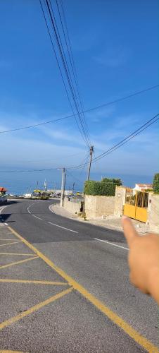 a hand pointing at an empty road with the ocean at Mega Ocean Magoito - Sintra in Sintra