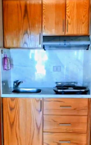 eine Küche mit Holzschränken und einem Herd mit Backofen in der Unterkunft Ad un passo dalle stelle 56 domina coral bay in Sharm El Sheikh
