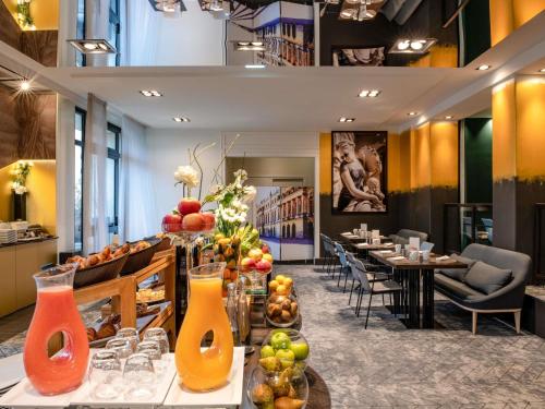 Un restaurante con mesas y sillas y jarrones llenos de jugo. en Le Louis Hotel Versailles Château - MGallery Collection, en Versalles