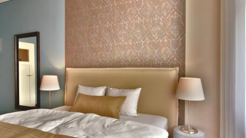 - une chambre avec un lit, deux lampes et un miroir dans l'établissement Carl.22 City Appartements, à Eisenach