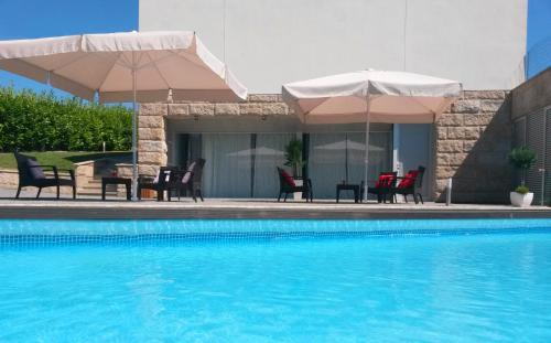 a swimming pool with chairs and umbrellas and a table and chairsktop at Equinaturi in Santo Tirso