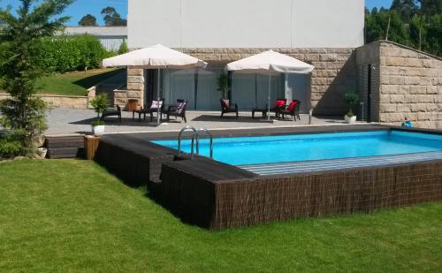 a swimming pool in a yard with chairs and umbrellas at Equinaturi in Santo Tirso