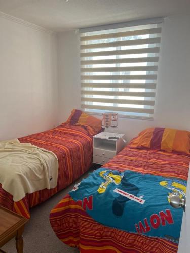 two beds sitting next to each other in a bedroom at Cómodo departamento in El Tabo