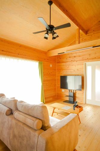 a living room with a couch and a ceiling fan at Matsushima hill bungalow in Matsushima