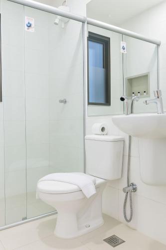 a white bathroom with a toilet and a sink at Vida Plaza Hotel in Brasília