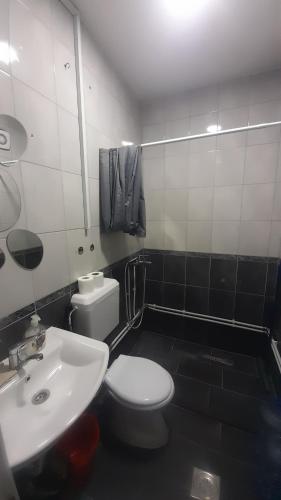 a bathroom with a white toilet and a sink at Central Flat in Prizren