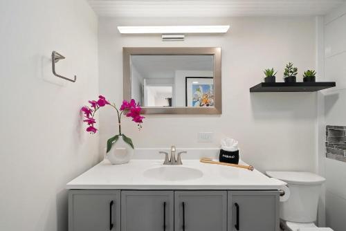 baño con lavabo y jarrón con flores en Lauloa 403 · LOA 403 Fully Remodeled Direct Oceanfront 2BD, en Wailuku