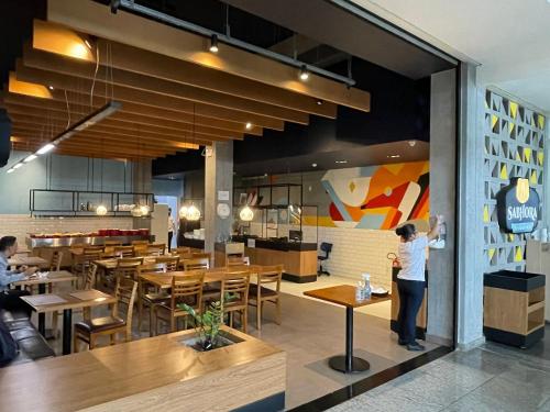 una persona de pie en un restaurante con mesas y sillas en iFlat BTLX Brookfield Towers BTLX2807, en Goiânia