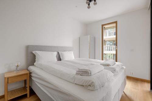 ein großes weißes Bett in einem weißen Zimmer mit Fenster in der Unterkunft Moderne leilighet i Vannkunsten Syd in Oslo