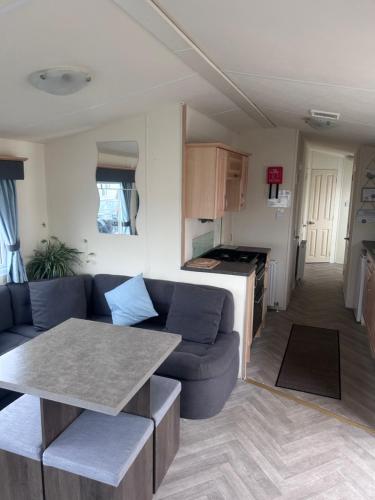 ein Wohnzimmer mit Sofa und Tisch in der Unterkunft Spacious 10 birth Caravan Golden palm resort chapel st leonards Skegness in Chapel Saint Leonards