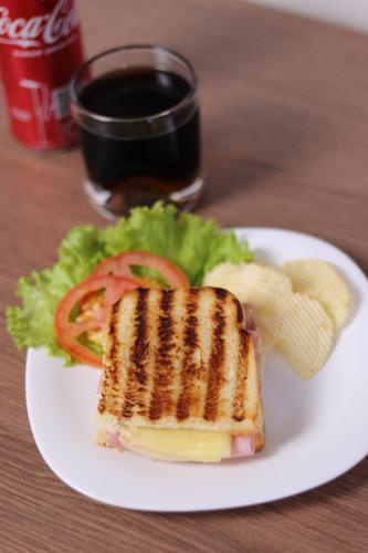 Un sándwich y ensalada en un plato con un vaso de refresco. en Vida Plaza Hotel, en Brasilia