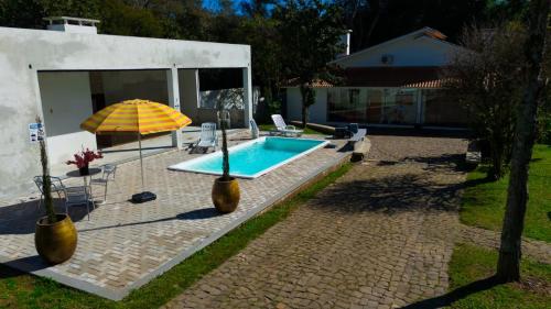 - une piscine avec un parasol, des chaises et une table dans l'établissement Pousada CHÂTEAU LUMIÈRE, à Itaara