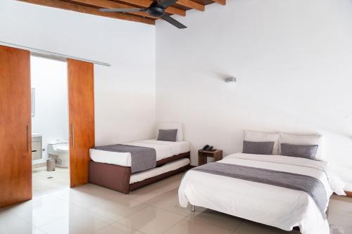 a bedroom with two beds and a bathroom at Hotel Laureles Loft in Medellín