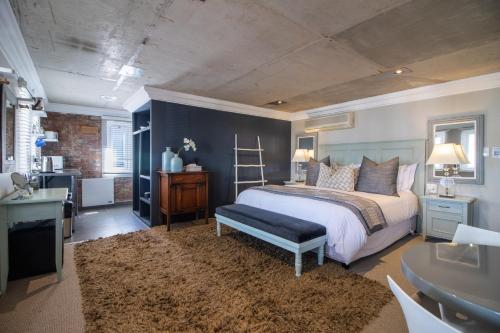 une chambre avec un lit et un bureau et une salle de bain dans l'établissement Thesen Harbour Town Apartments @ Beautiful Knysna Villas, à Knysna