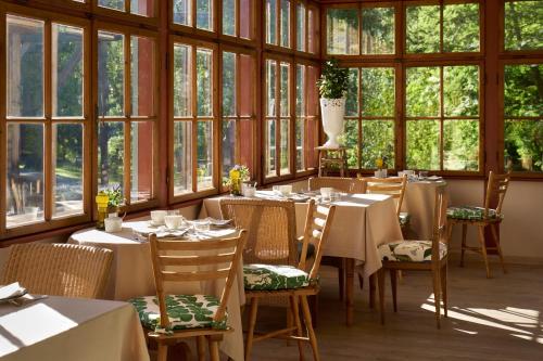 une salle à manger avec tables, chaises et fenêtres dans l'établissement Berghoferin Fine Hotel & Hideaway, à Redagno