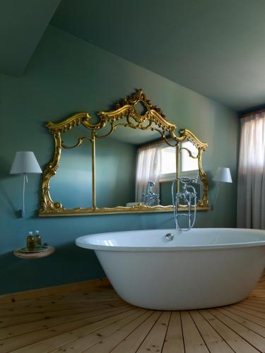 a white bath tub in a room with a mirror at Berghoferin Fine Hotel & Hideaway in Redagno