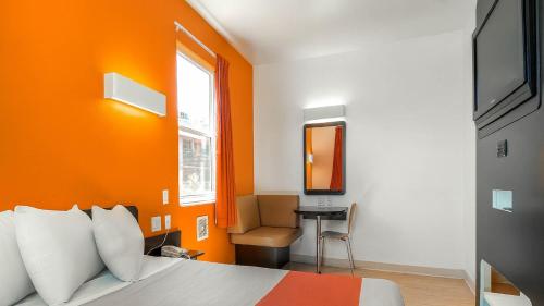a bedroom with orange walls and a bed and a chair at Motel 6-San Diego, CA - Downtown in San Diego