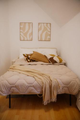 a bed in a bedroom with two pictures on the wall at Ferienwohnung zur kleinen Grede in Herborn