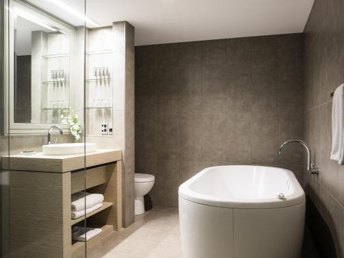 a bathroom with a tub and a toilet and a sink at Novotel Melbourne On Collins in Melbourne