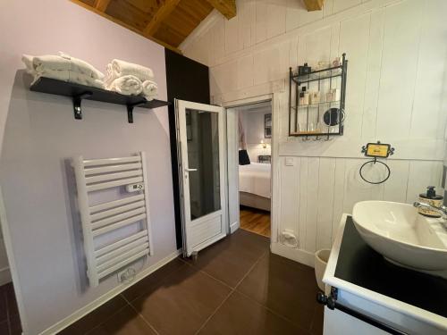 a bathroom with a sink and a mirror and a door at Les Rocailles in Lamonzie-Montastruc