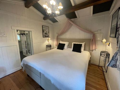 a bedroom with a large white bed and a chandelier at Les Rocailles in Lamonzie-Montastruc