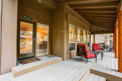 a porch with red chairs and a table and windows at Big Pine in Bend