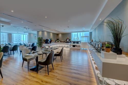 a restaurant with tables and chairs in a building at TRYP by Wyndham Abu Dhabi City Center in Abu Dhabi