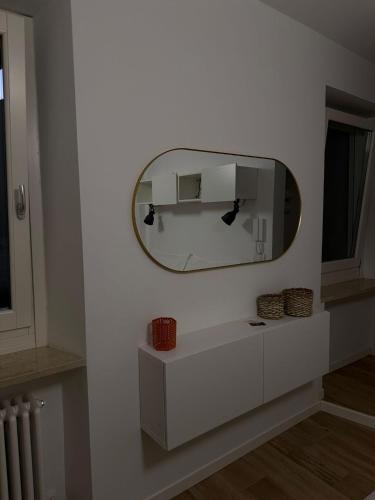 a mirror on a white wall with a white cabinet at Le Casette in Macerata