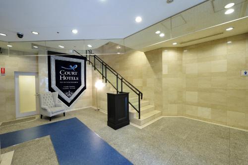 a lobby with a staircase and a sign for a hotel at Court Hotel Shin-Yokohama in Yokohama