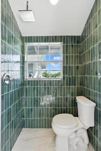 a green tiled bathroom with a toilet and a window at The Cowboy Social Unit 10 in Williams